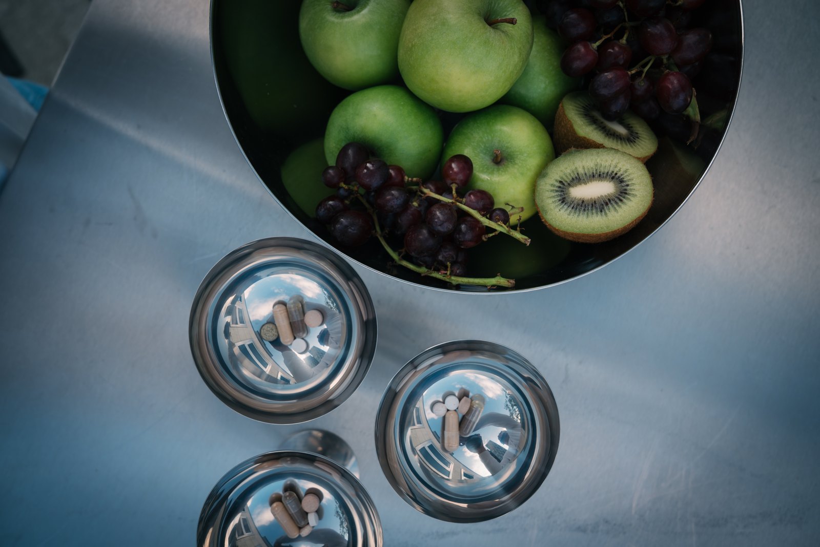Obstschale und Edelstahlbecher mit vorportionierten ERA ONE Kapseln auf einem Tisch